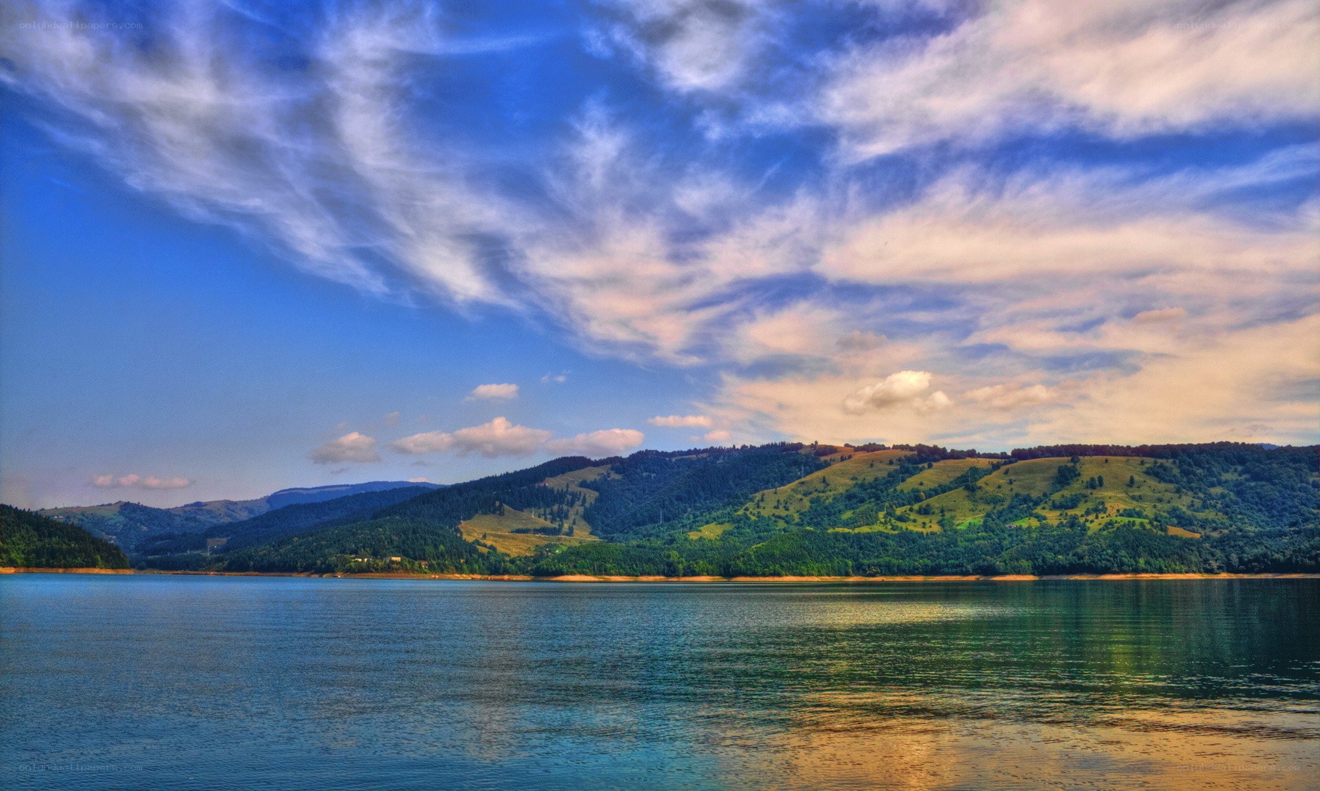 Lake with hills under cloudy sky