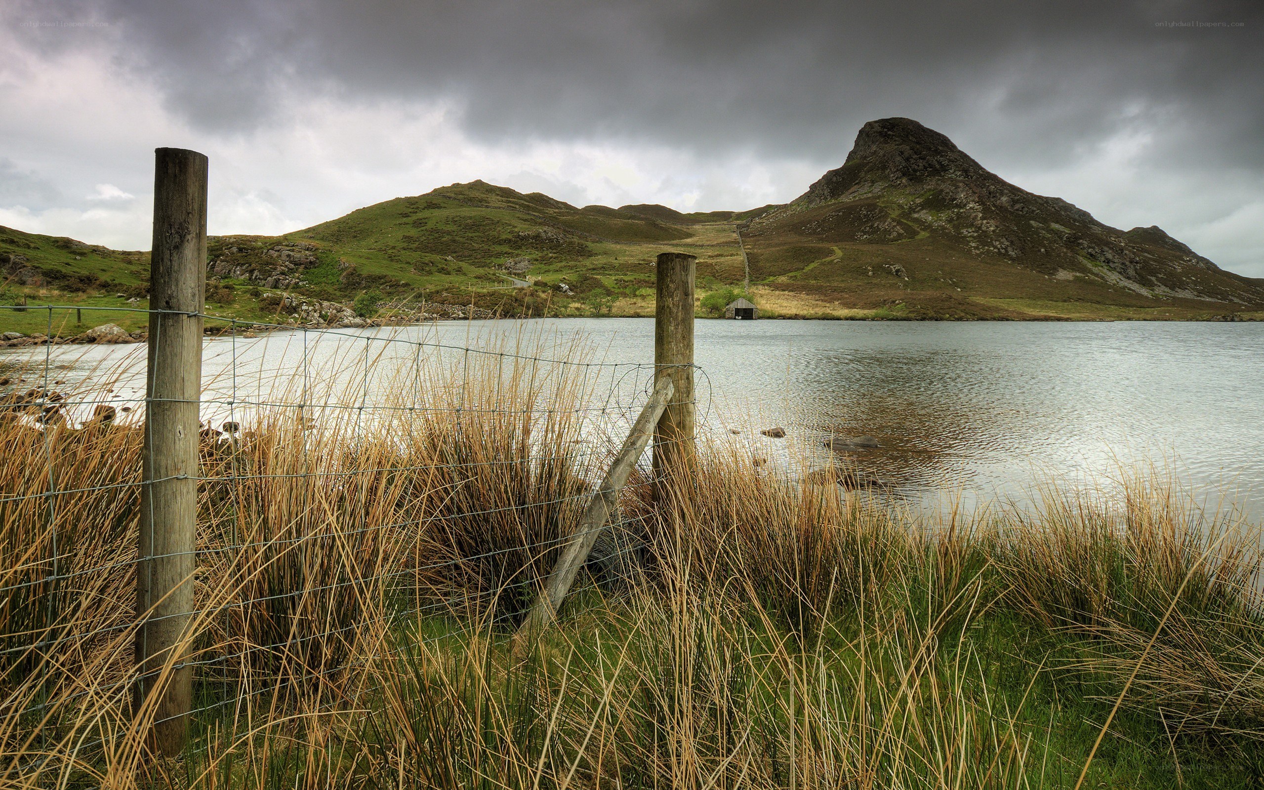 Lake with hills under cloudy sky