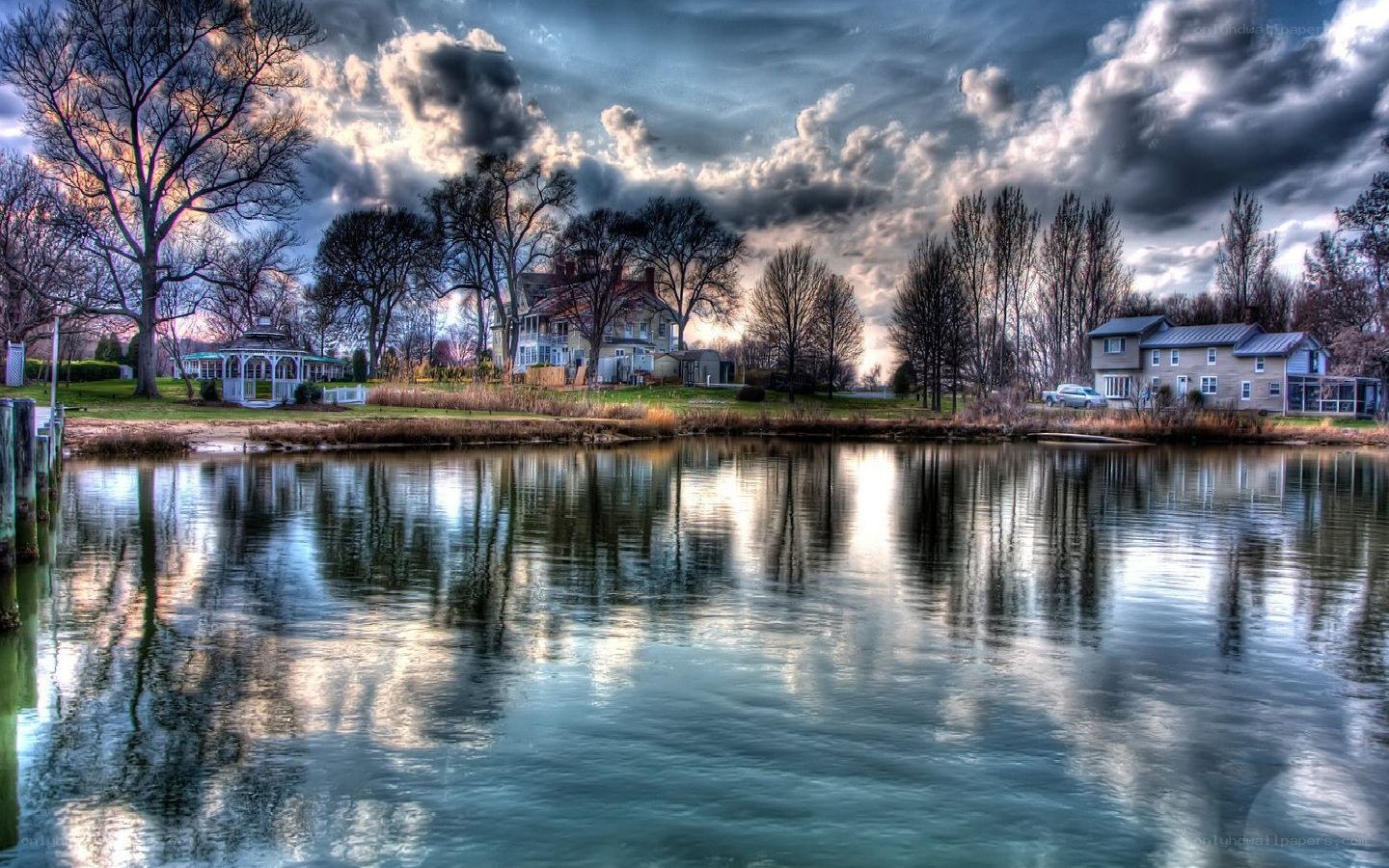 Lake with houses and cloudy sky