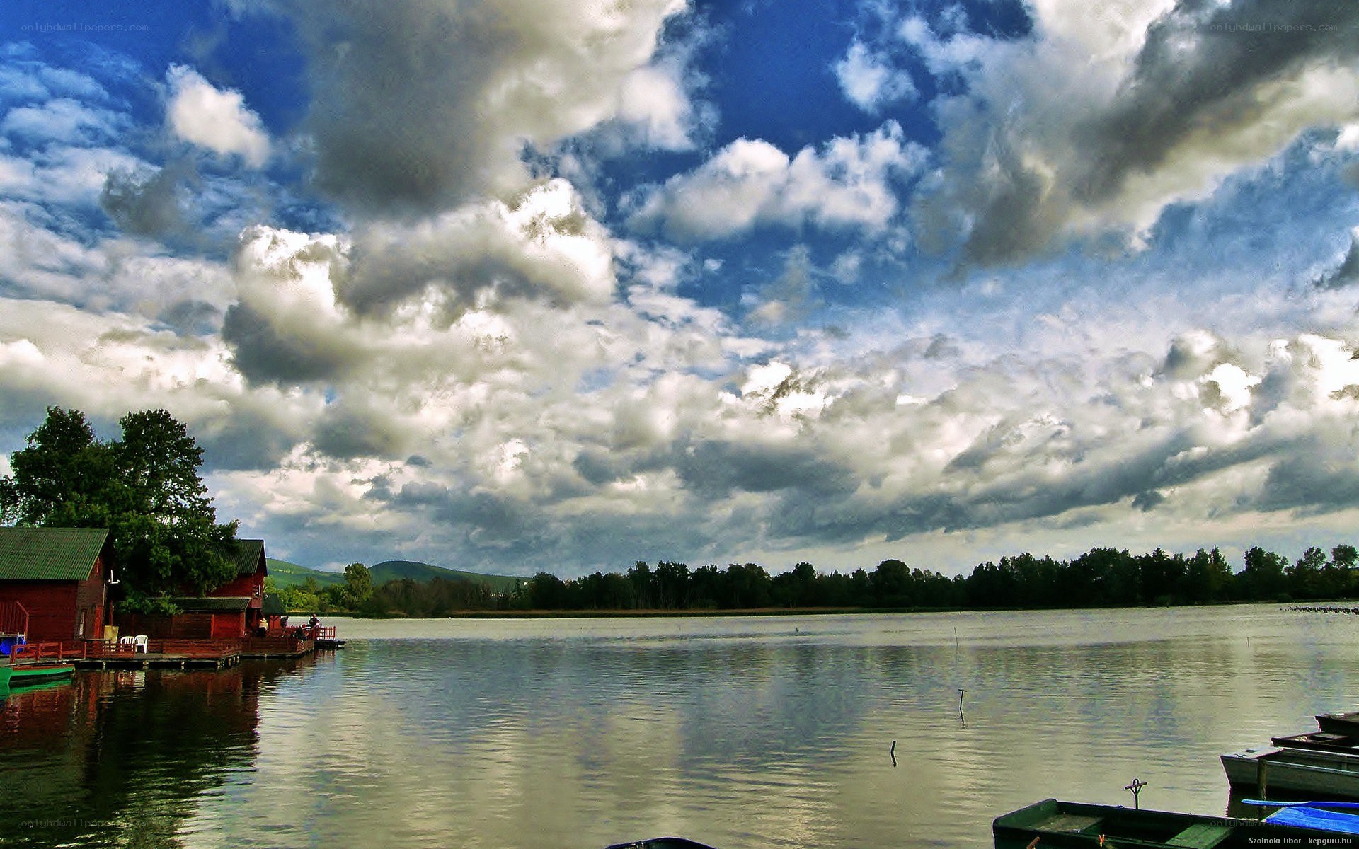 Lake with red cabins and cloudy sky