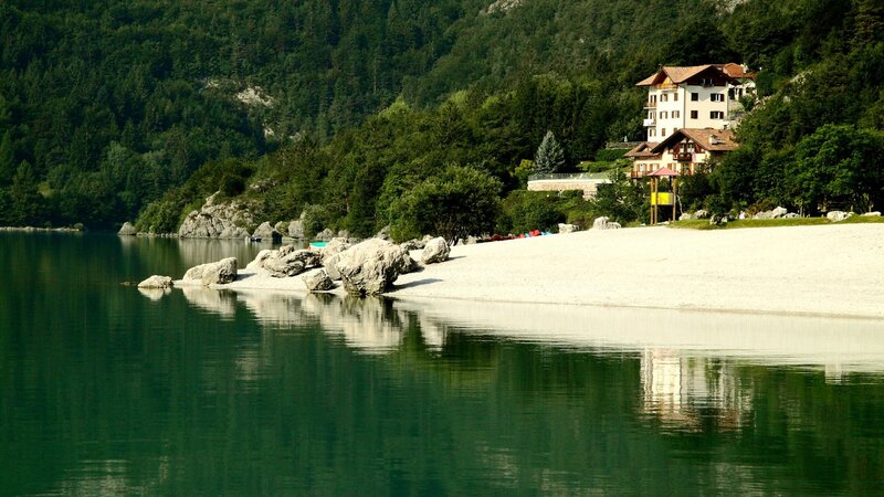 Lake with sandy beach and mountain house