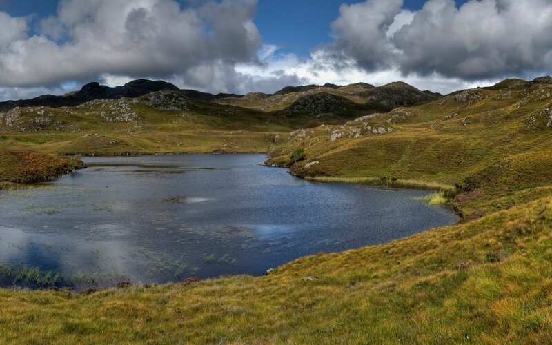 Lakeside hills under cloudy sky