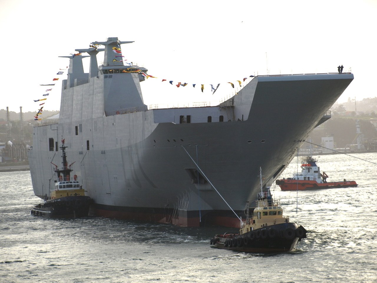 Large naval ship with tugboats