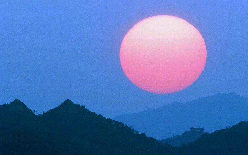 Large Pink Sun over Mountains