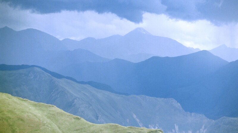 Layered mountain ranges under cloudy sky