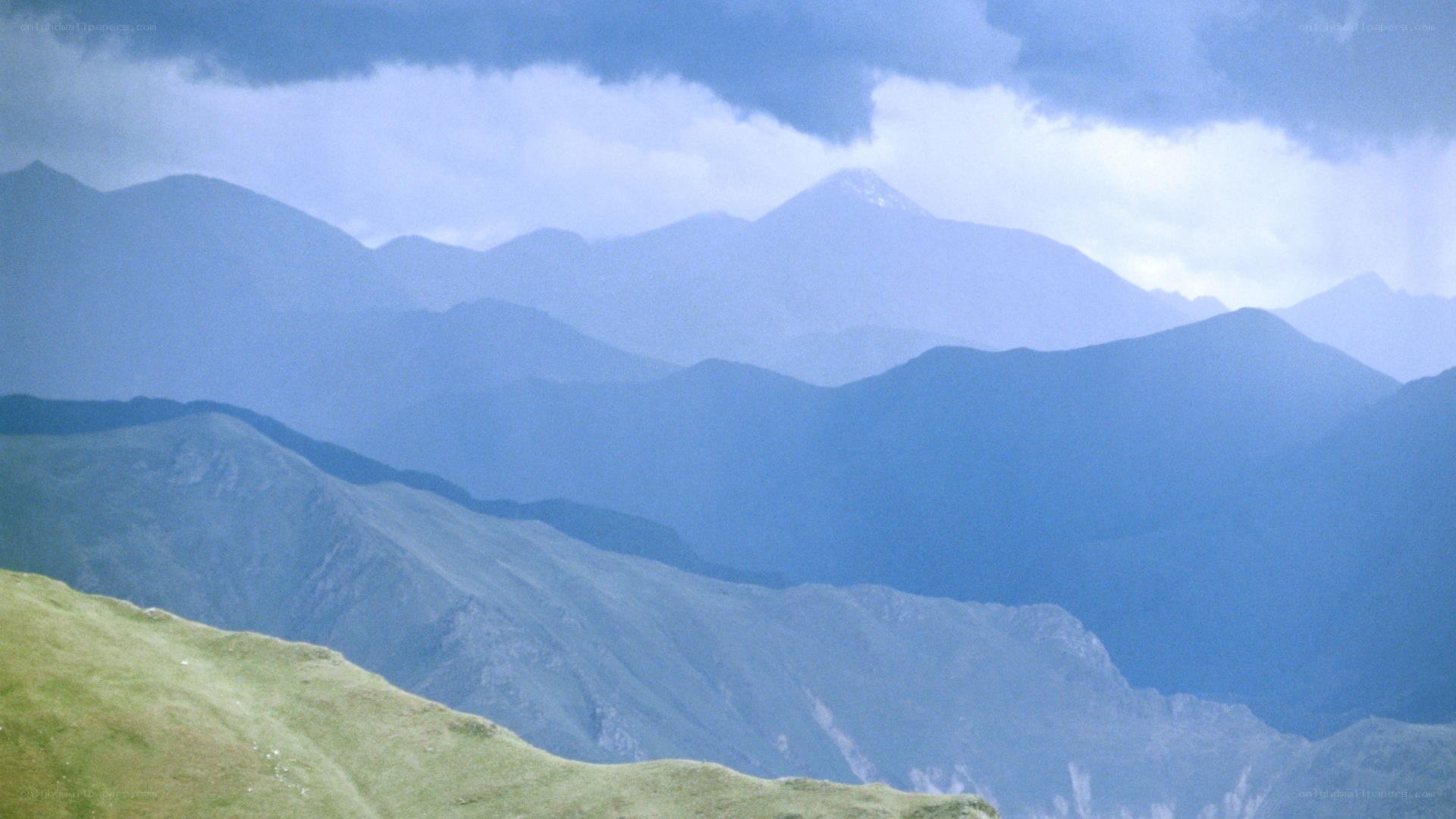 Layered mountain ranges under cloudy sky