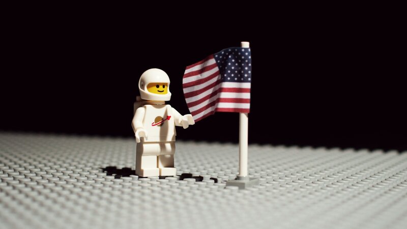 Lego Astronaut with Flag — White, Dramatic, Photograph, Space Suit