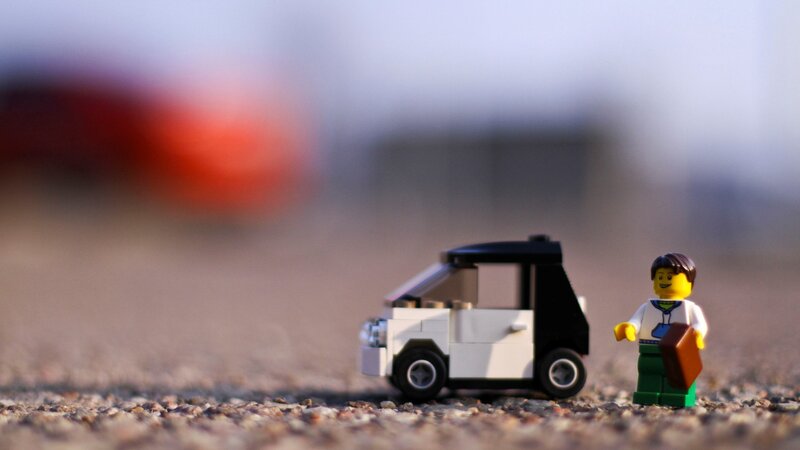 Lego figure with car on gravel