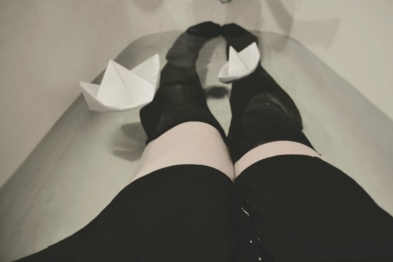 Legs in bathtub with paper boats