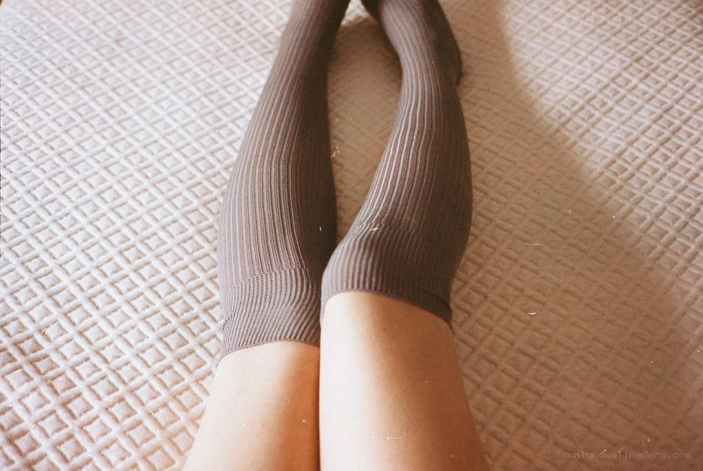 legs in brown socks on bed