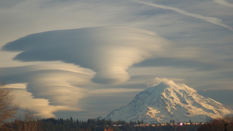 Lenticular clouds over a snow-capped mountain