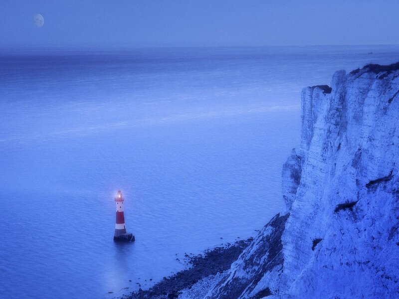 Lighthouse at dusk by cliffs