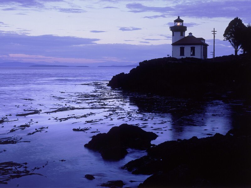 Lighthouse at dusk on rocky coast