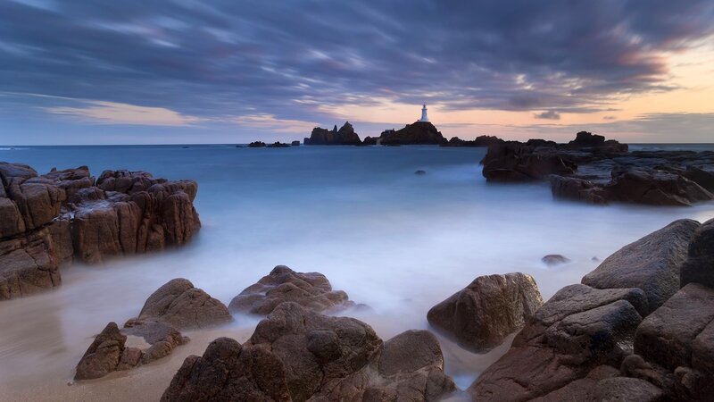 Lighthouse at dusk on rocky coast