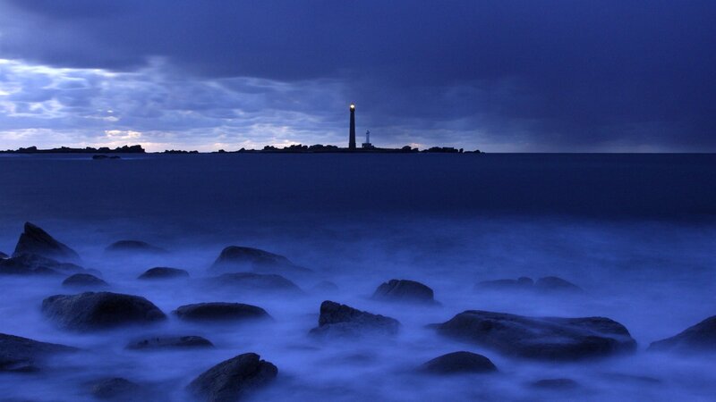 Lighthouse at dusk on rocky shore
