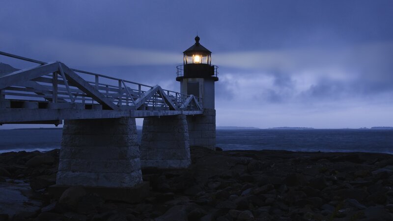 lighthouse at dusk on rocky shore