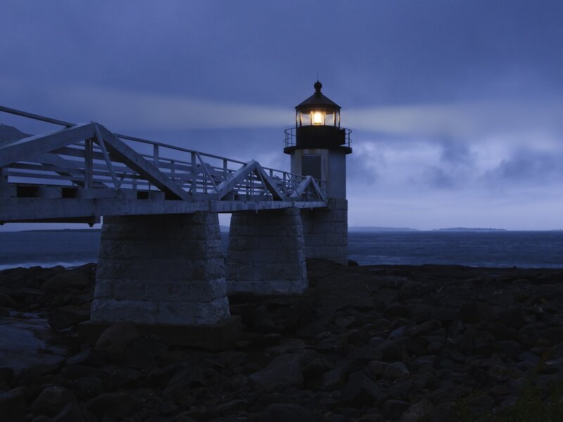 Lighthouse at dusk on rocky shore