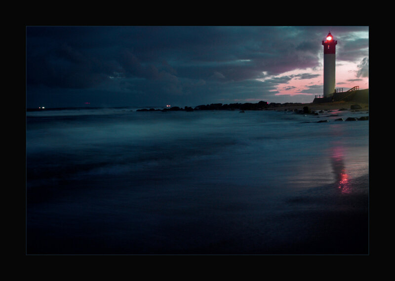 lighthouse at dusk on rocky shore