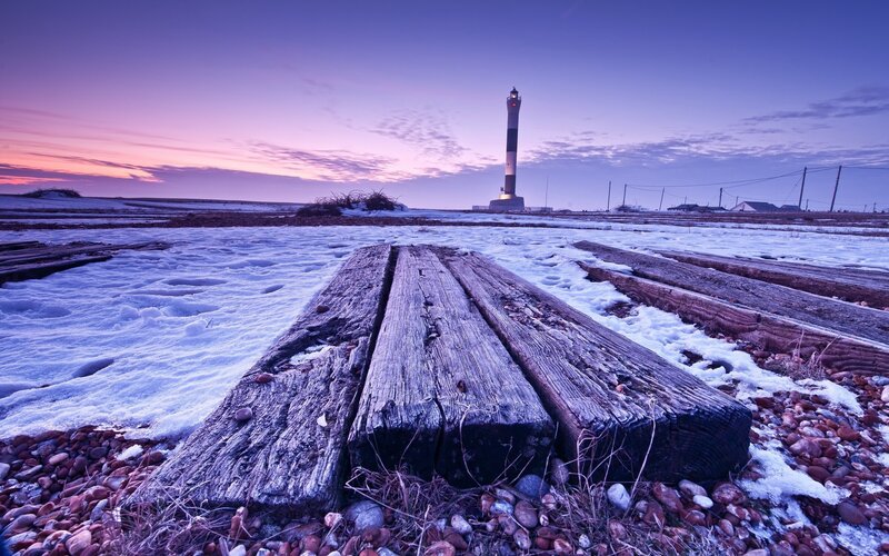 Lighthouse at dusk on snowy shore
