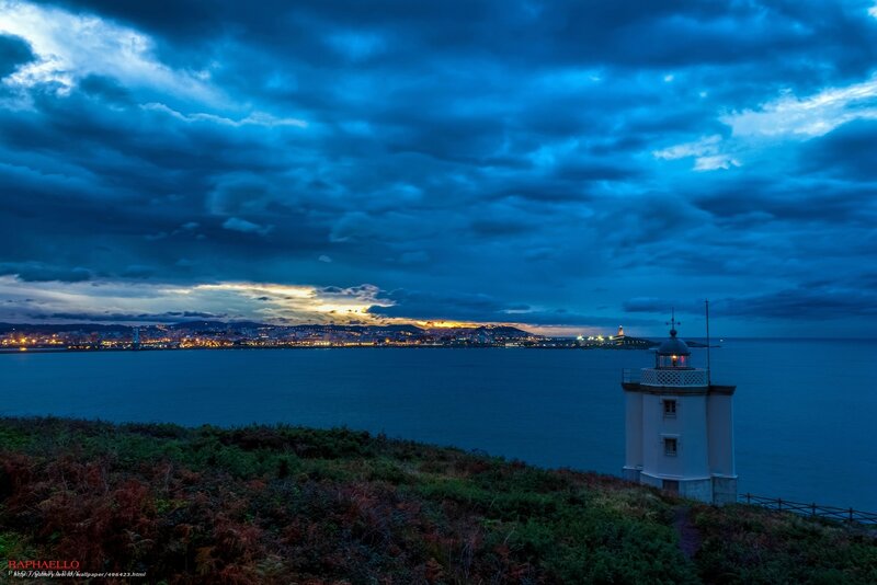 Lighthouse at dusk overlooking a coastal city