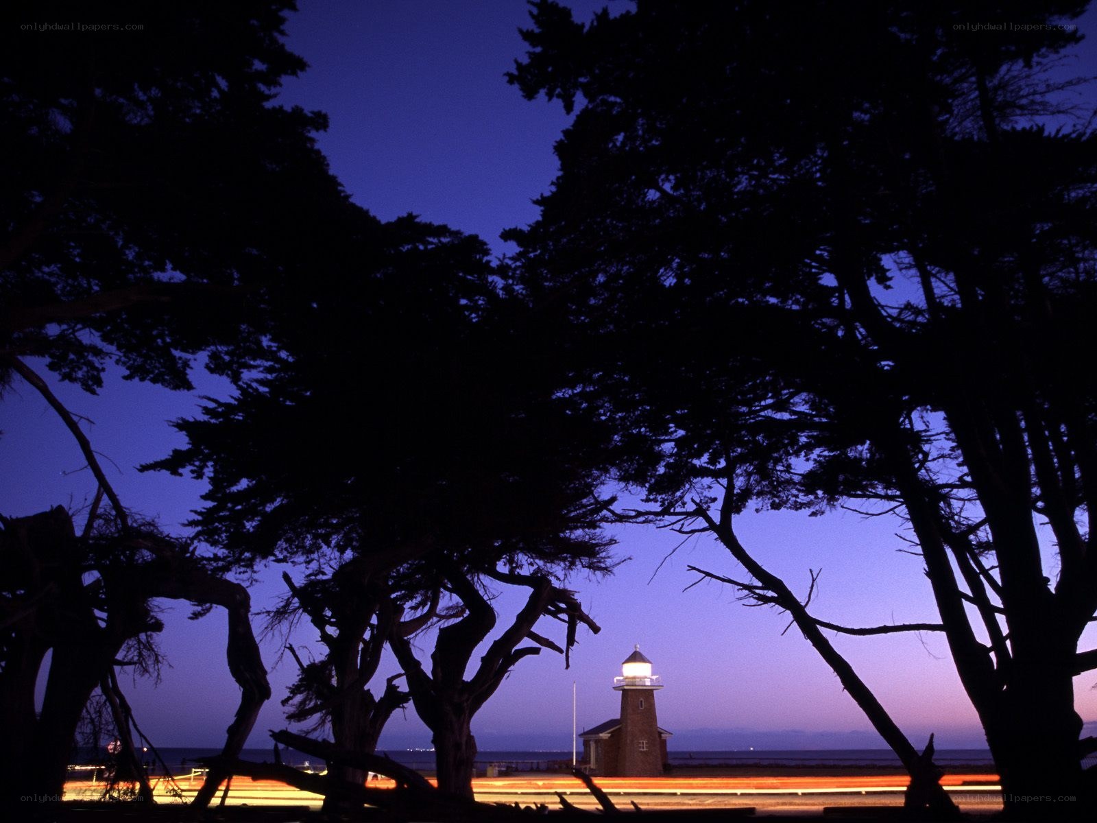 Lighthouse at dusk with tree silhouettes