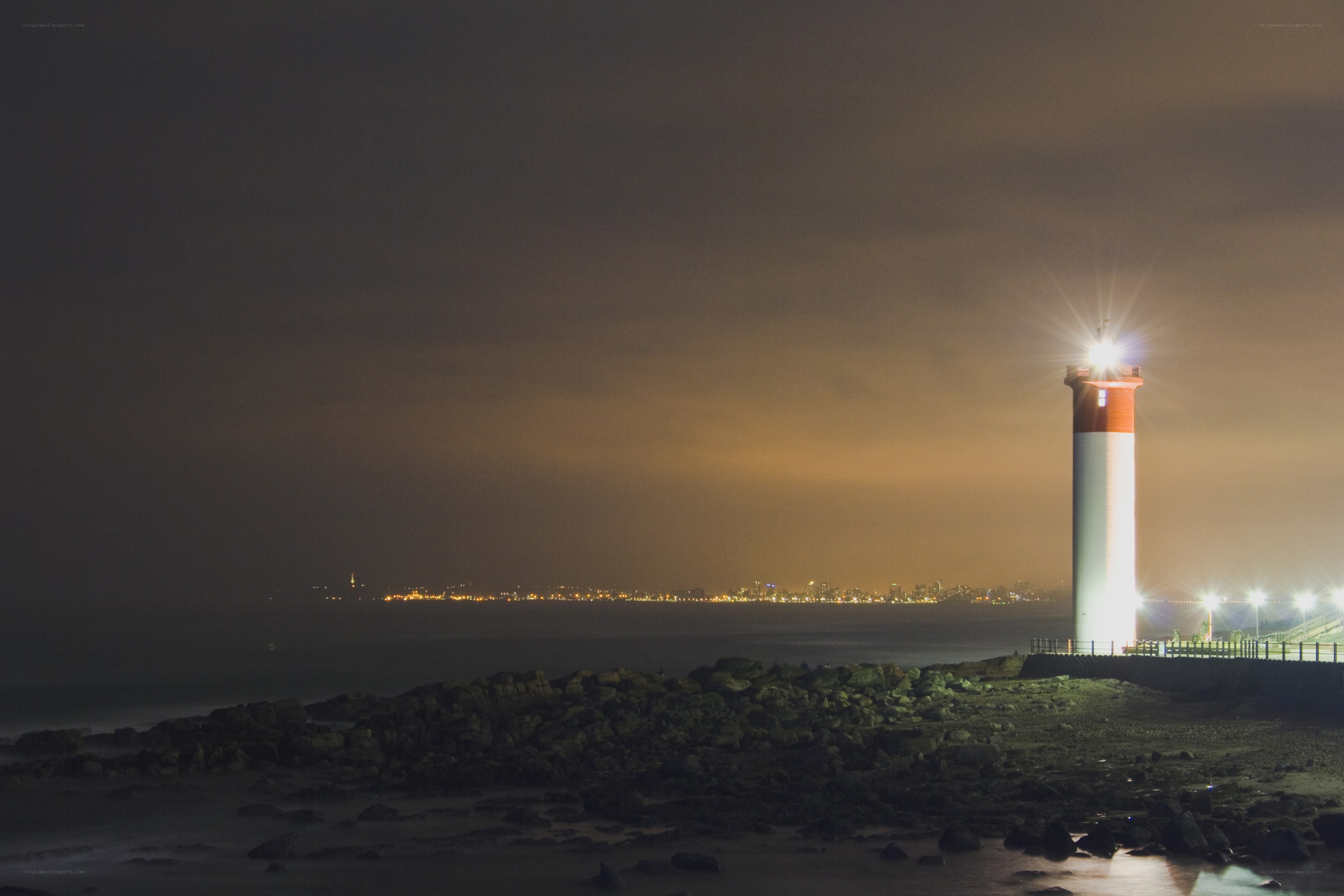 lighthouse at night with city view