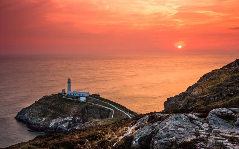 Lighthouse at sunset on a rocky coast