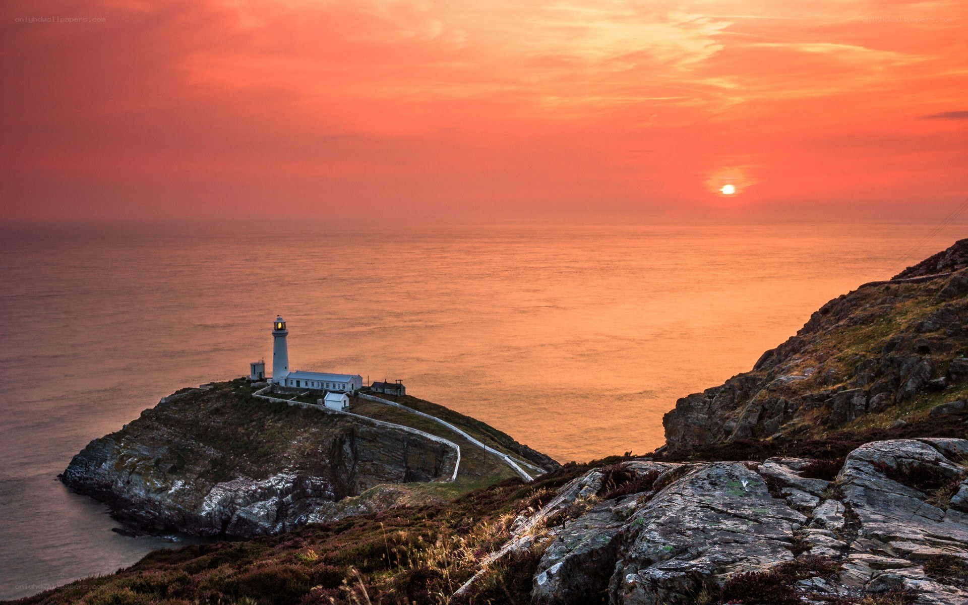 Lighthouse at sunset on a rocky coast