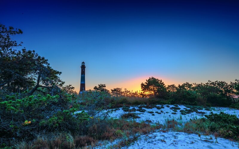 Lighthouse at sunset on a sandy dune