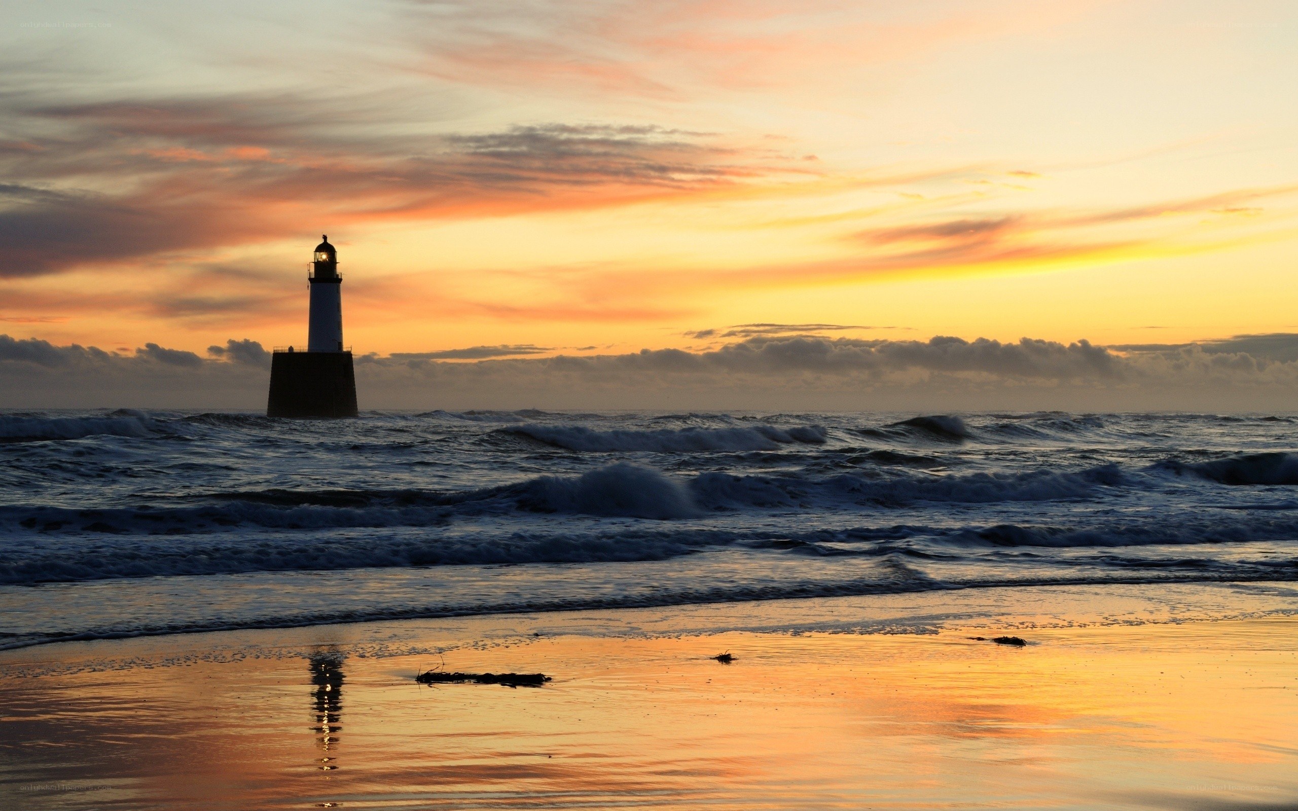 Lighthouse at sunset on a stormy beach