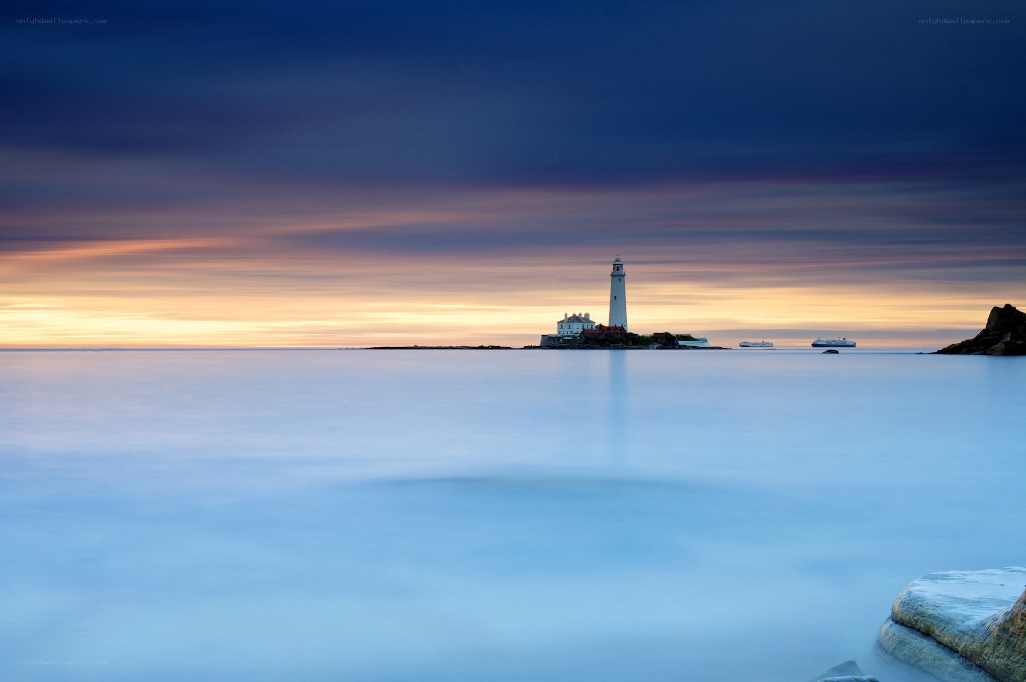 Lighthouse at sunset on calm sea