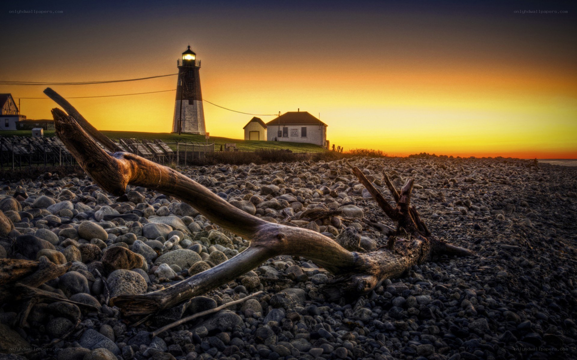Lighthouse at sunset on rocky beach