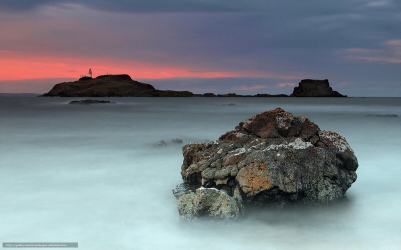 Lighthouse at sunset on rocky coast