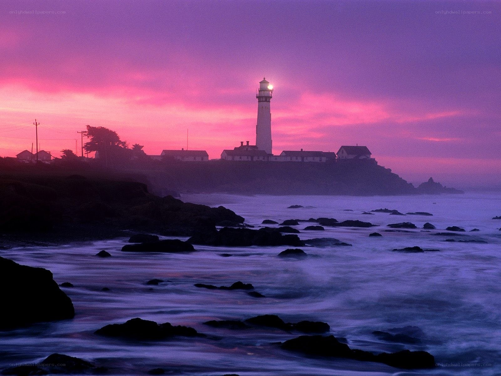 lighthouse at sunset on rocky coast