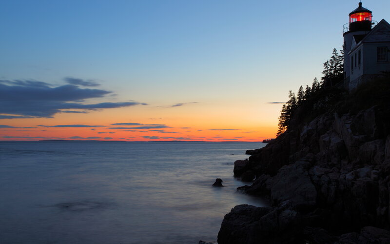 lighthouse at sunset on rocky coast