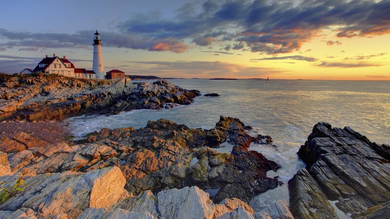 lighthouse at sunset on rocky coast