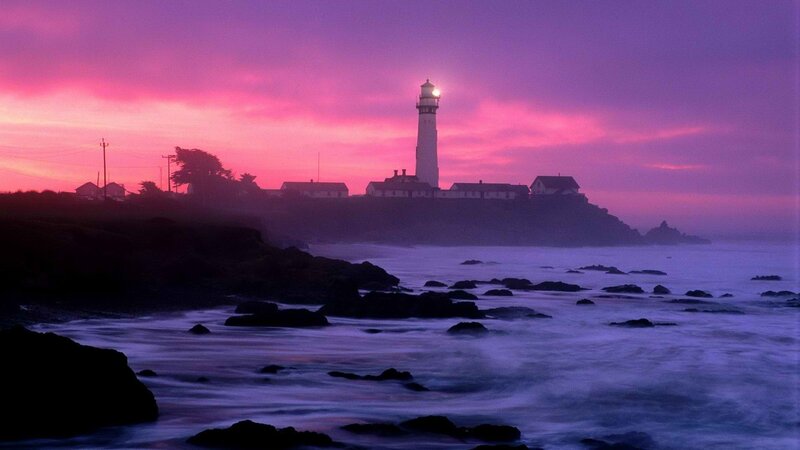 lighthouse at sunset on rocky coast