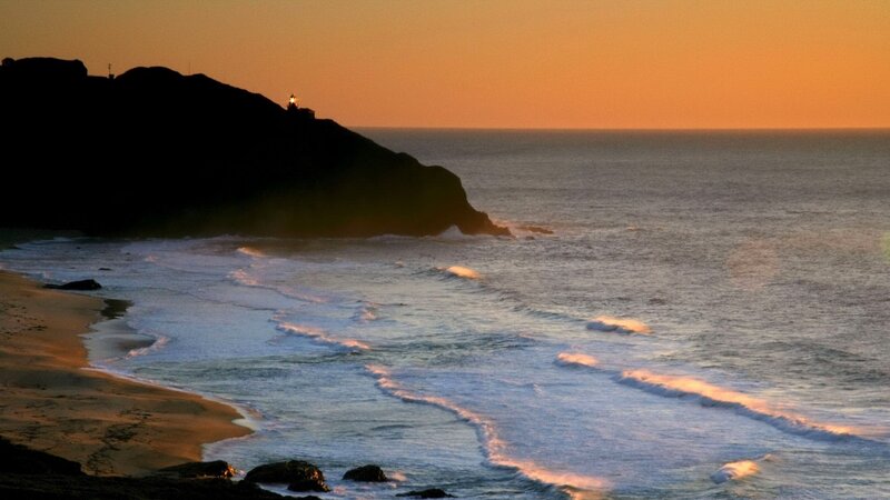 lighthouse at sunset on rocky coast