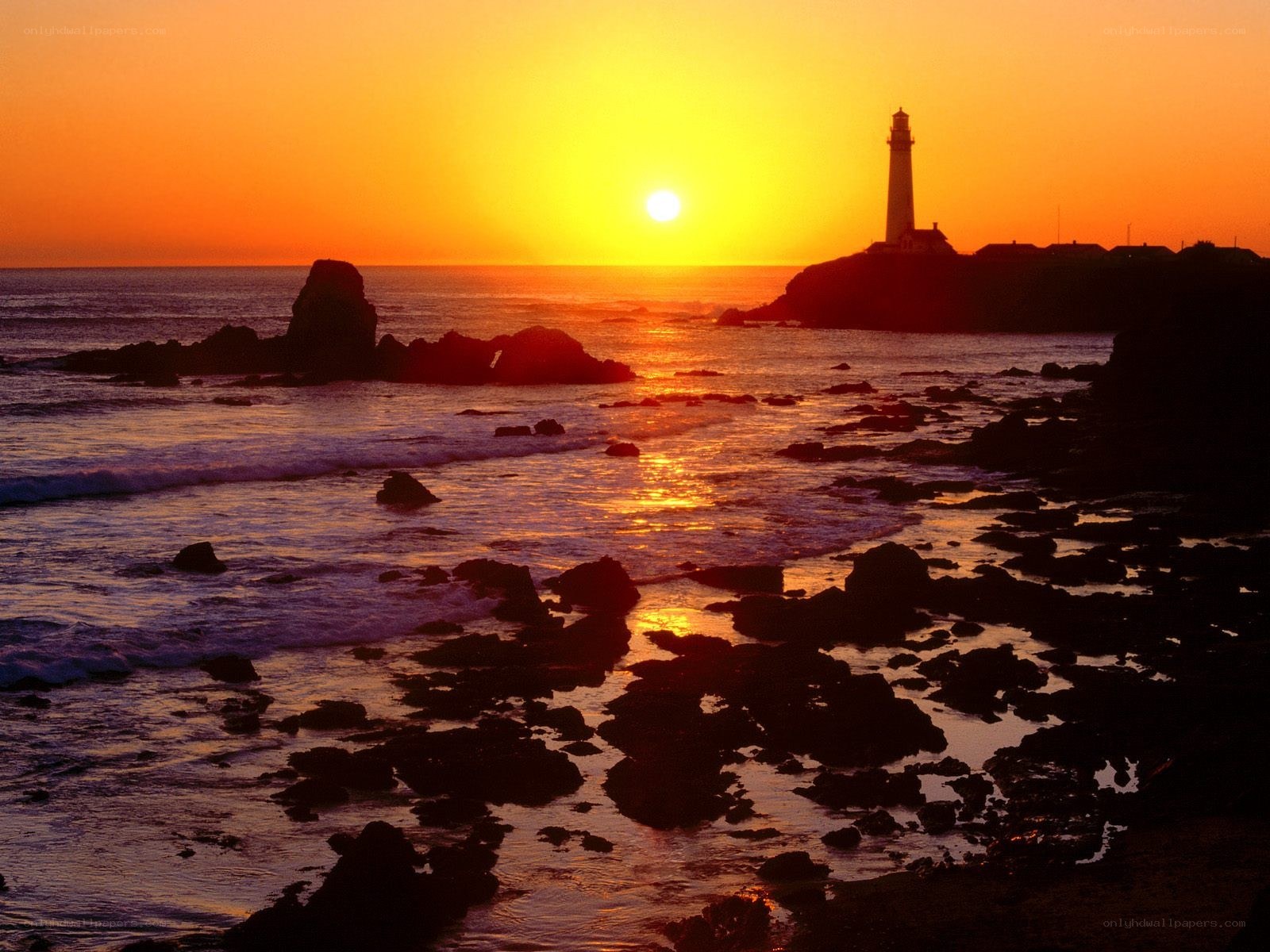 Lighthouse at sunset on rocky coast