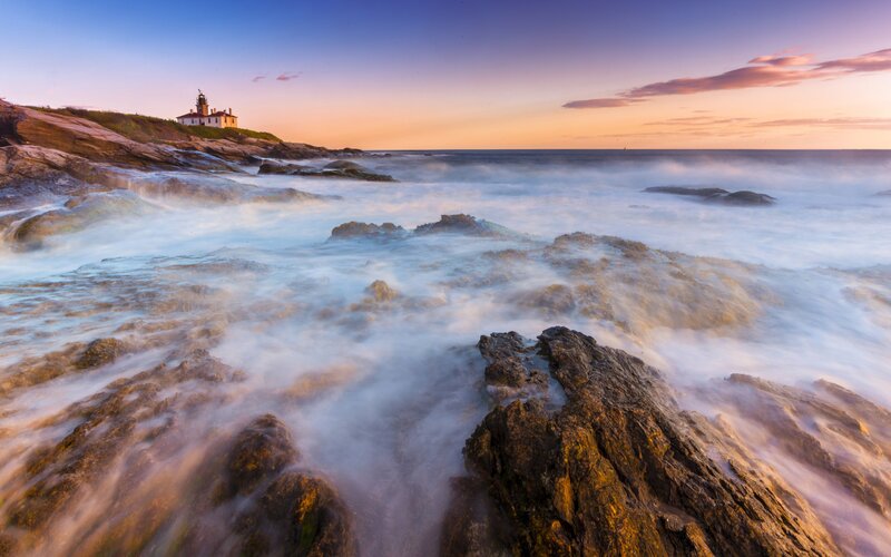 Lighthouse at sunset on rocky coast