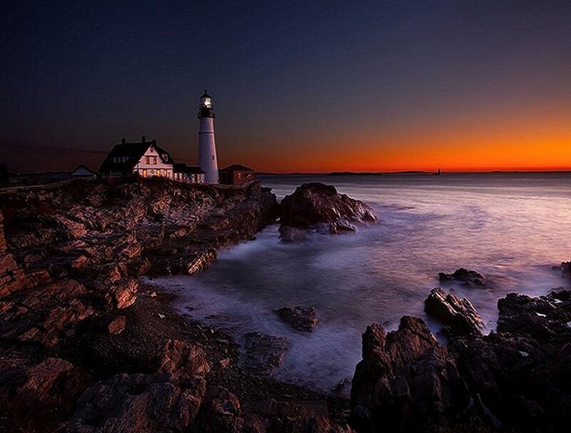 lighthouse at sunset on rocky coast