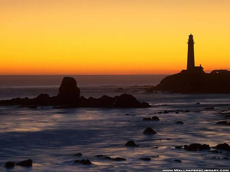 lighthouse at sunset on rocky coast