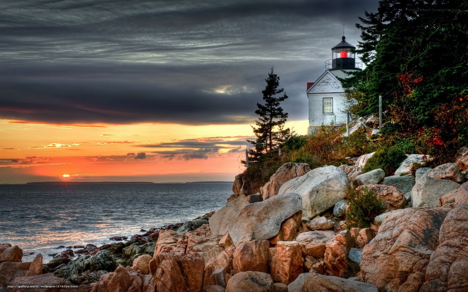 Lighthouse at sunset on rocky coast