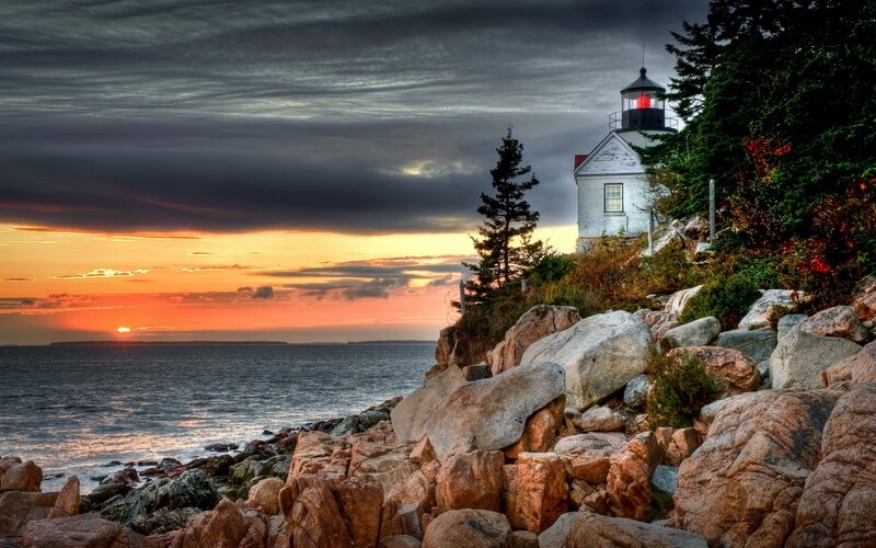 Lighthouse at sunset on rocky coast