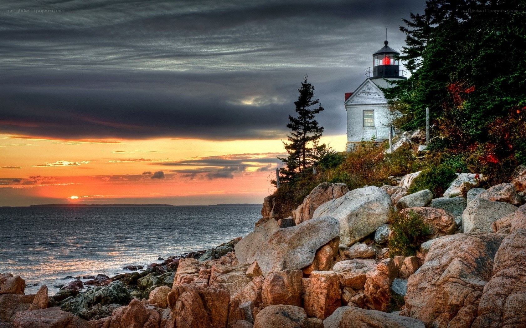 Lighthouse at sunset on rocky coast