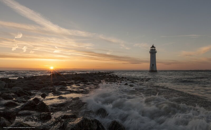 Lighthouse at sunset on rocky shore