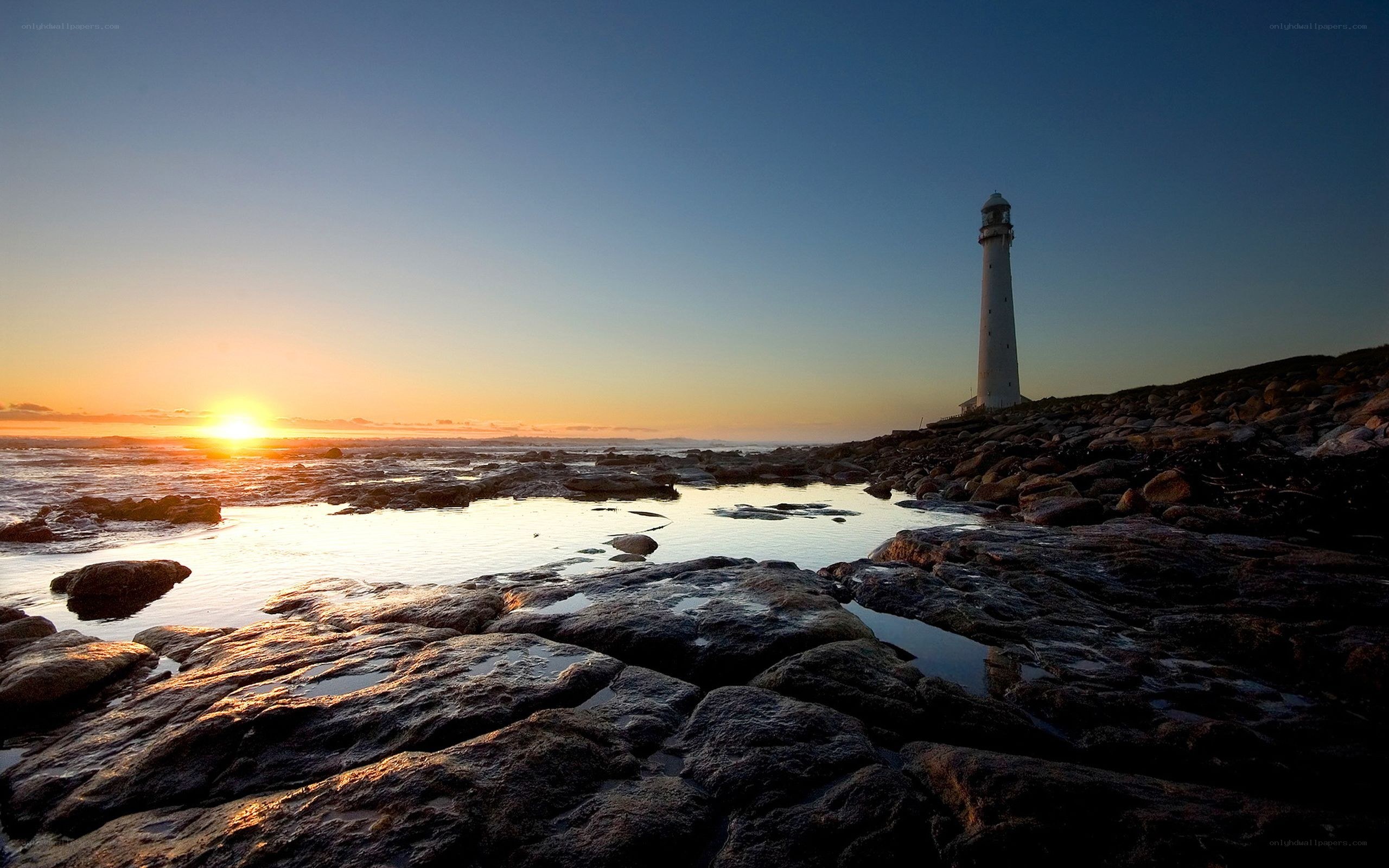 Lighthouse at sunset on rocky shore