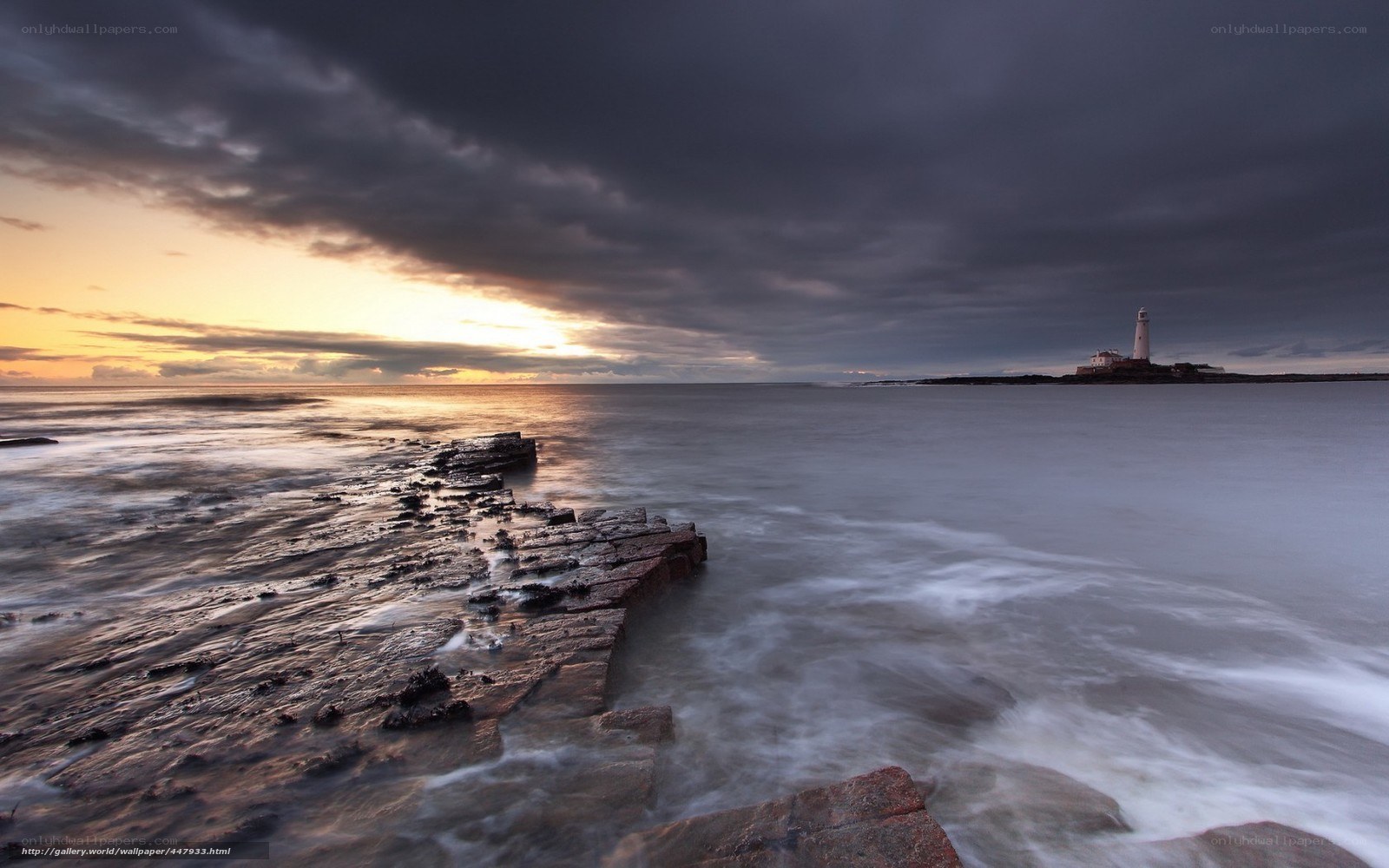 Lighthouse at sunset on rocky shore