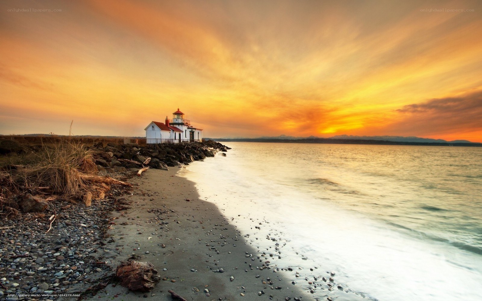 Lighthouse at sunset on rocky shore