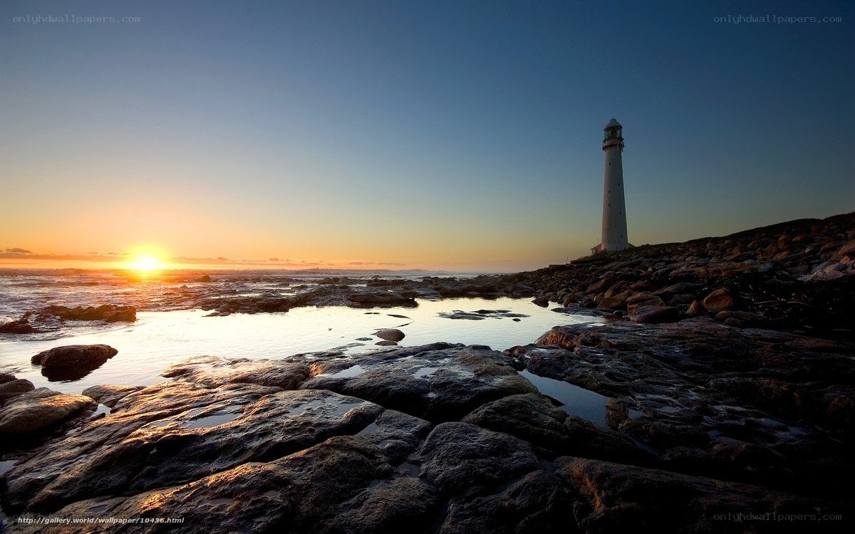 Lighthouse at sunset on rocky shore